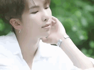 a close up of a young man wearing a white shirt and a watch .