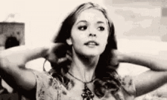 a black and white photo of a woman holding her hair in a ponytail .