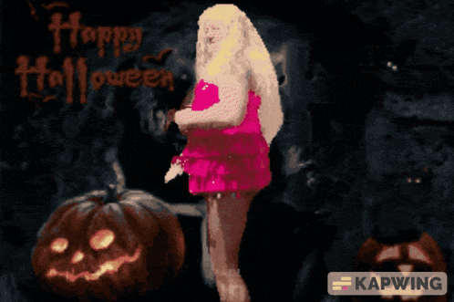 a woman in a pink dress is standing in front of pumpkins with the words happy halloween written on the wall behind her