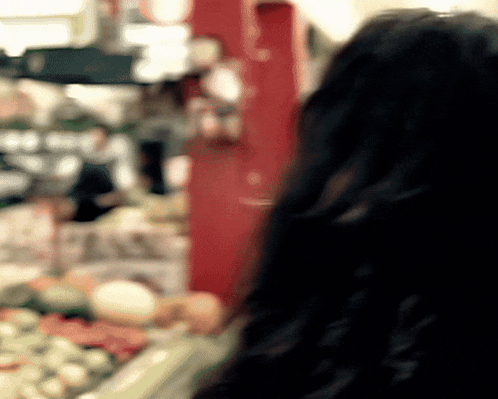 a blurry picture of a woman looking at vegetables in a store