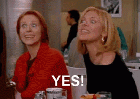 two women are sitting at a table in a restaurant and one of them is smiling and saying yes .