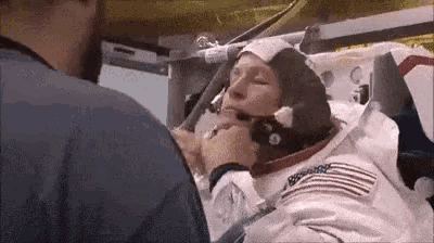 a man is putting a helmet on an astronaut .