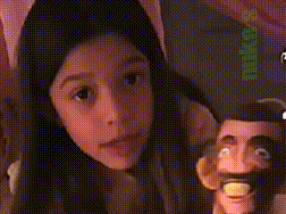 a girl is holding a puppet in front of a sign that says " niko "