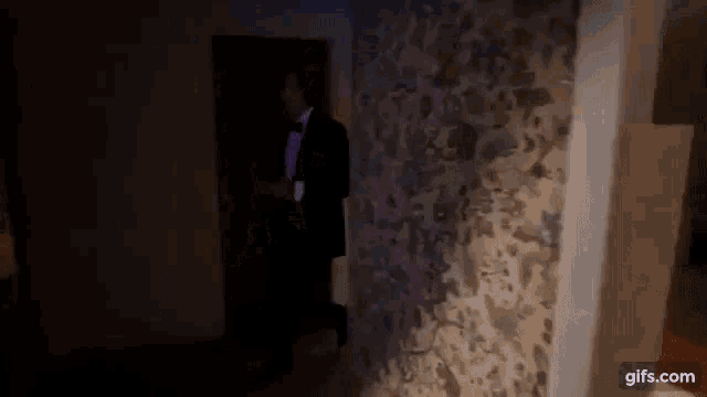 a man in a tuxedo and bow tie is walking through a doorway .