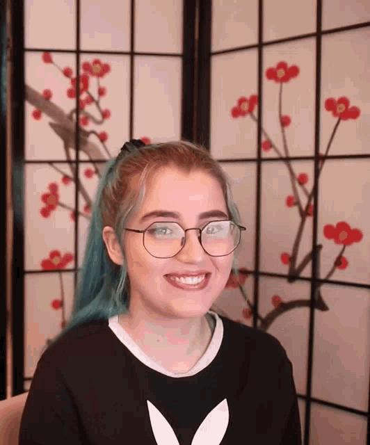 a girl with blue hair wearing glasses and a black shirt with a bunny on it