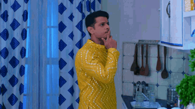 a man in a yellow kurta is standing in a kitchen