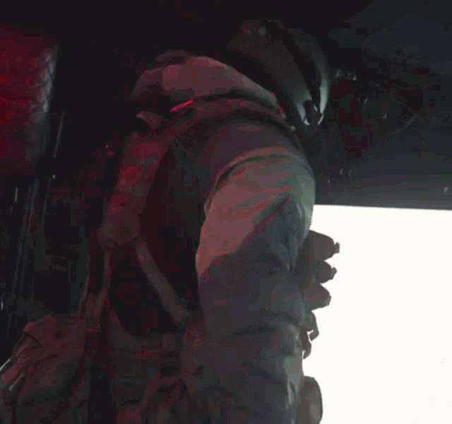 a man wearing a helmet and a vest is looking down