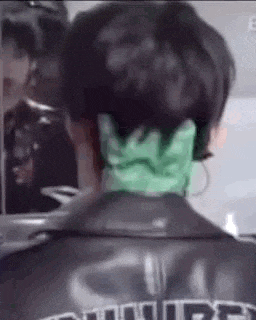 a close up of a person 's back with a green glove on their neck .