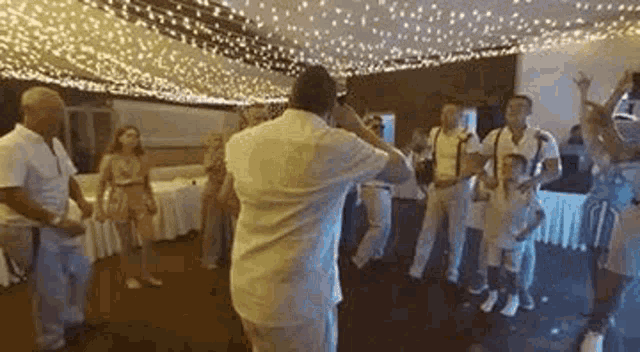 a group of people are dancing in a room with a lot of lights on the ceiling .