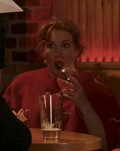 a woman in a red sweater drinks through a straw