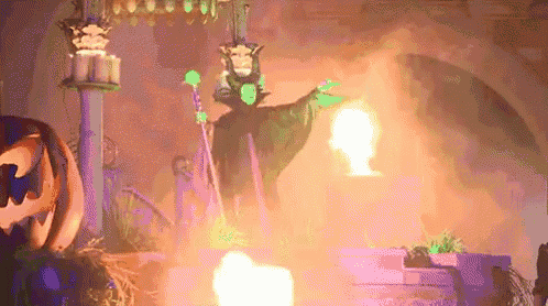 a witch is standing in front of a fire and a pumpkin in a dark room .