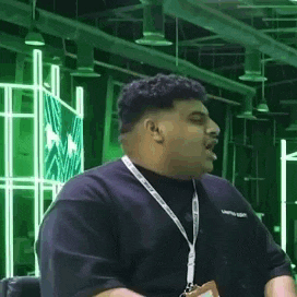 a man wearing a lanyard and a black shirt is sitting in a chair .