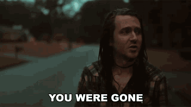 a man with long hair and dreadlocks is standing on a street and saying `` you were gone '' .