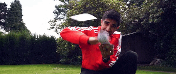 a man in a red adidas jacket throws a frisbee in the air