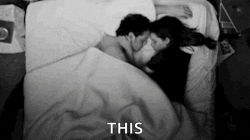 a man and a woman are laying in bed kissing .