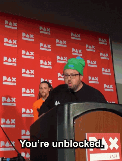 a man stands at a podium with the words you 're unblocked