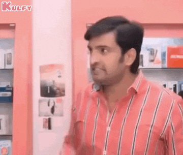 a man in a pink striped shirt is standing in front of a pink wall in a store .