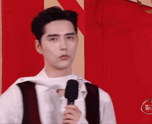a man is holding a microphone in front of a red and white wall