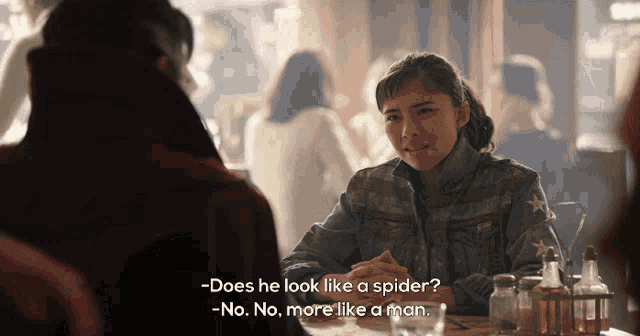 a man and a woman are sitting at a table and the woman says does he look like a spider