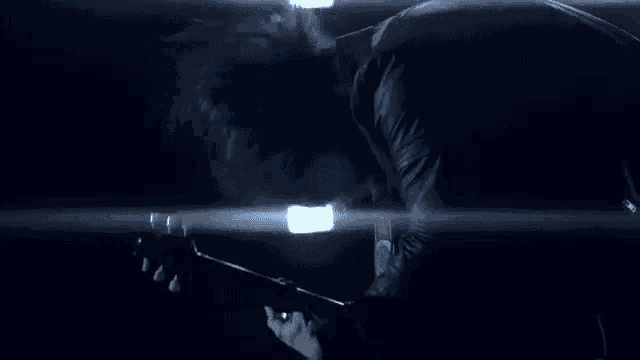 a man is playing a guitar in a dark room in front of a light .