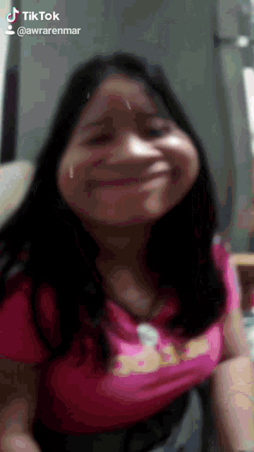 a girl in a pink shirt is making a funny face and has a tiktok account