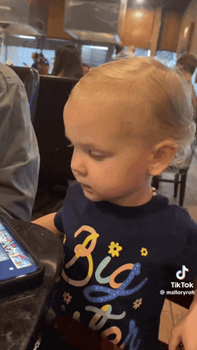 a little girl is wearing a blue shirt that says big sister .
