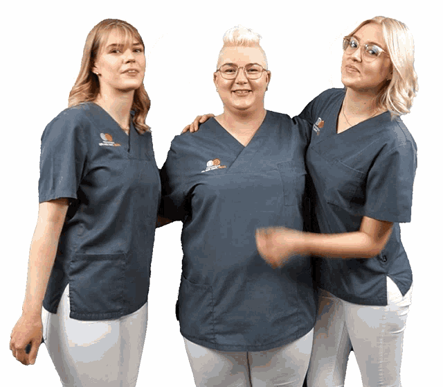 three women are posing for a picture with one wearing a scrub that says ' dental ' on it