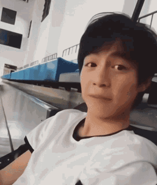 a young man in a white shirt is sitting in a chair