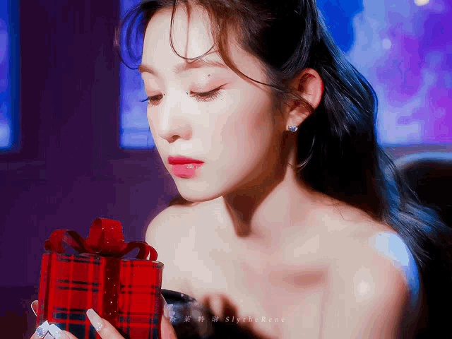 a woman is holding a red box with a red bow