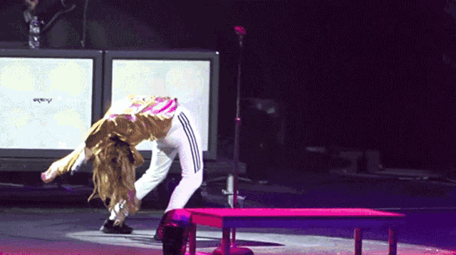 a woman stands on her knees on a stage with a microphone in front of a wall that says amplifier