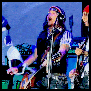 a man singing into a microphone while another man plays a guitar