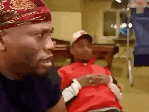 a man wearing a bandana is talking to a child sitting in a chair in a room .