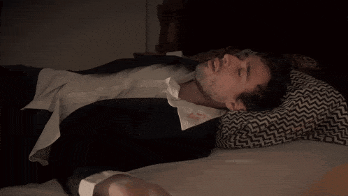 a man in a suit is laying on a bed with a pillow