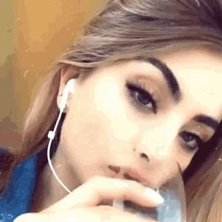 a close up of a woman wearing headphones and holding a glass of water