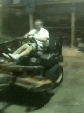 a man is sitting in a lawn mower in a garage .