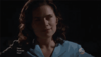 a woman is smiling in front of a microphone in a dark room .