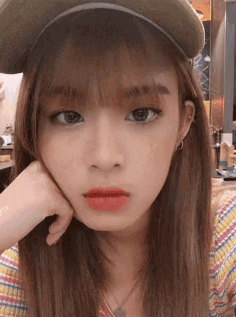 a woman wearing a hat and a striped shirt is looking at the camera