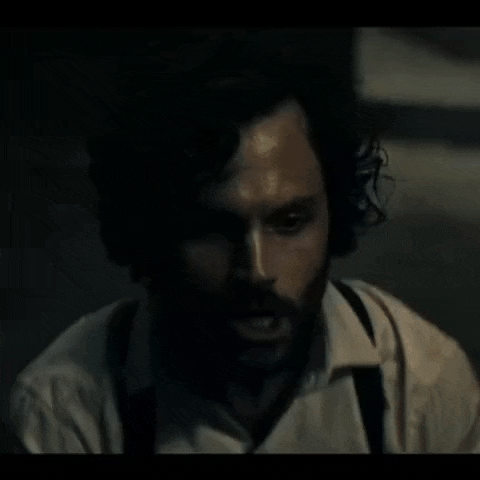 a man with a beard and suspenders is looking at the camera