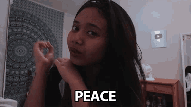 a girl making a peace sign with her hands around her neck
