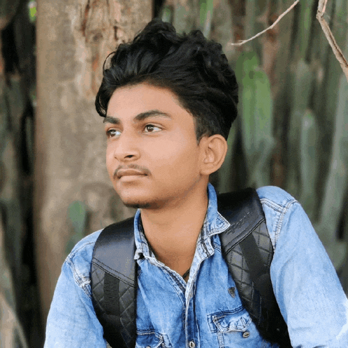 a young man in a denim shirt with a black backpack