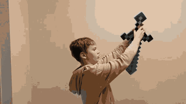 a young boy is holding a minecraft sword in his hands
