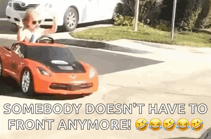 a little boy is driving a toy car down the street .