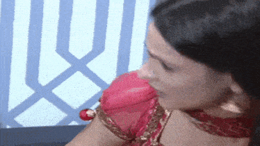 a woman in a red blouse is sitting on a couch and looking at something .