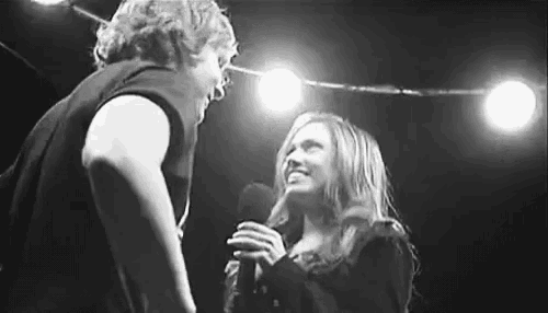 a man and a woman are standing next to each other on a stage holding microphones .