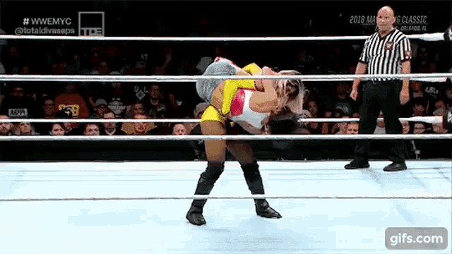 a woman is wrestling another woman in a ring with a referee watching .
