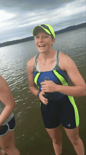 a woman in a blue tank top and black shorts stands in the water