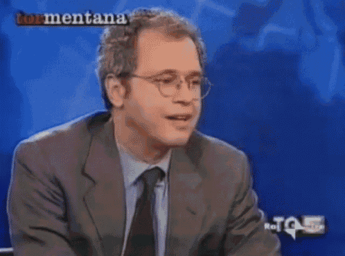 a man in a suit and tie is sitting in front of a blue screen with the word tormentana on it