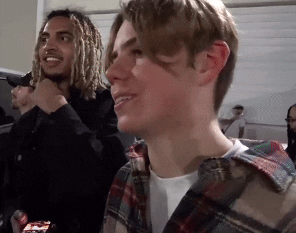 a group of young men are sitting in a room and one of them is smiling .