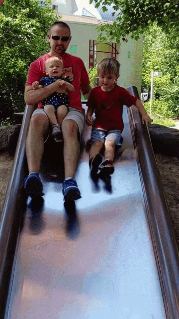 a man is sitting on a slide with two children