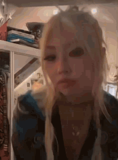 a woman with blonde hair and pigtails is standing in front of a closet .